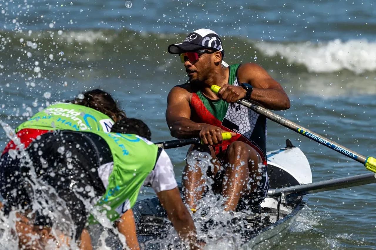 Coastal rowers scrambling into their boats at a beach sprint start