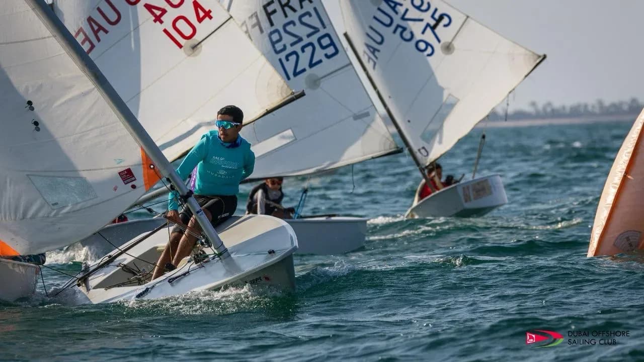 Optimist sailors sailing upwind in a tight pack