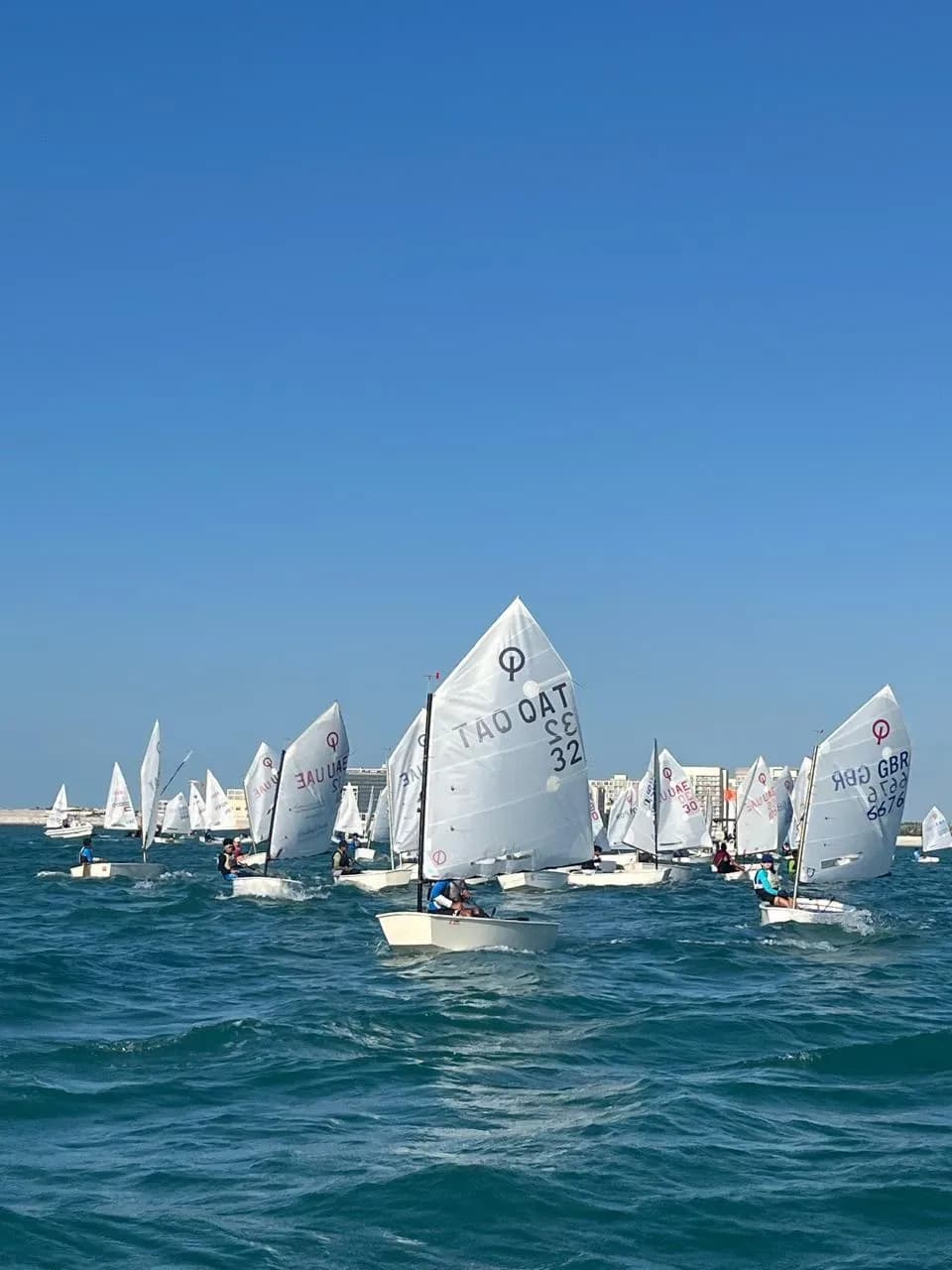 An Optimist fleet under a clear sky