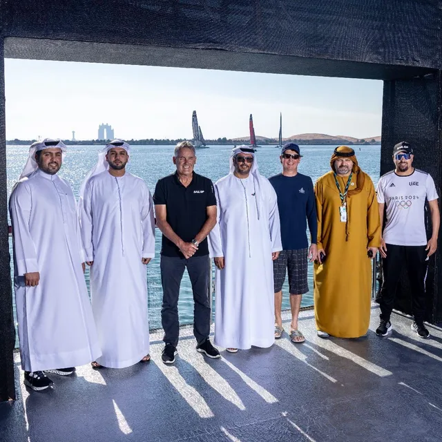 Officials on the viewing platform at a SailGP event, with the F50s racing behind